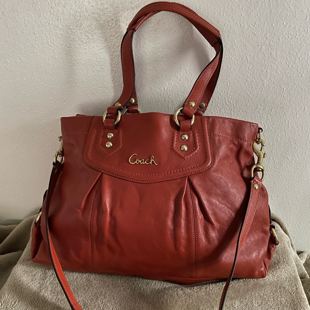 Burnt Orange / Rust Coach satchel with snap closure and shoulder strap.